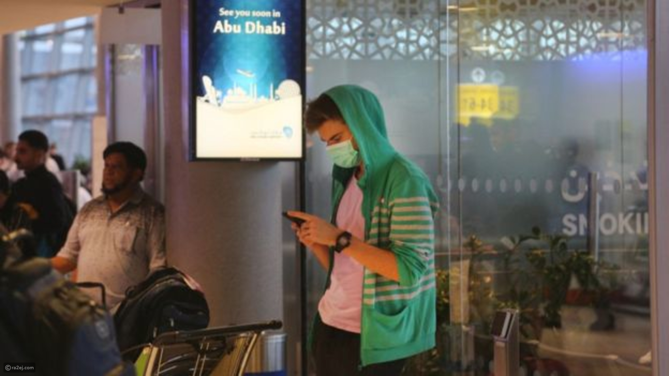 سائح بمطار أبو ظبي بالإمارات ينتظر مرتدياً الكمامة