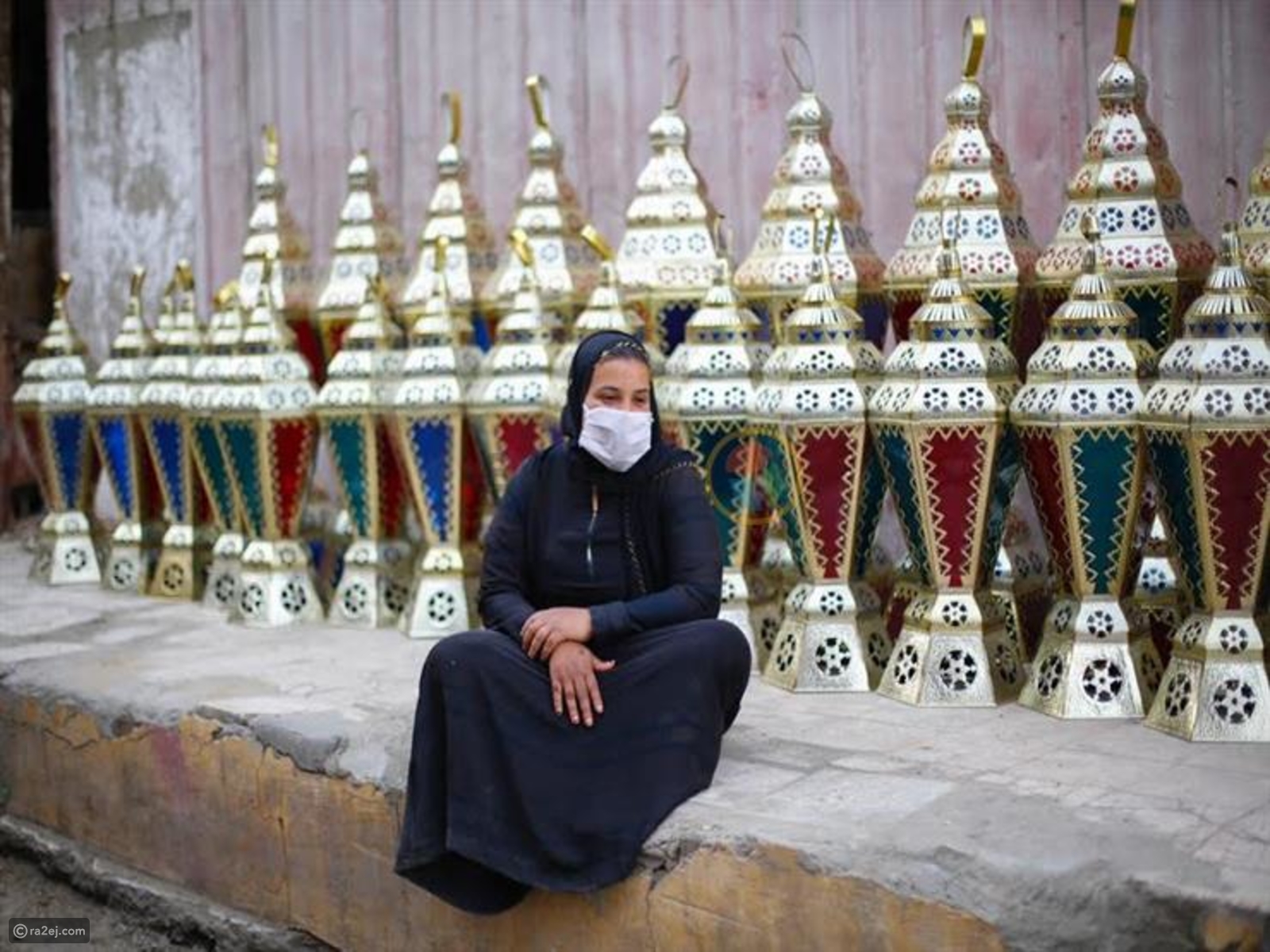 سيدة مصرية تجلس أمام الفوانيس وتضع الكمامة